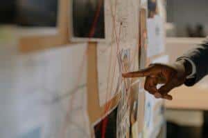 Close-up of an investigator pointing at an evidence board with connected clues using red strings.